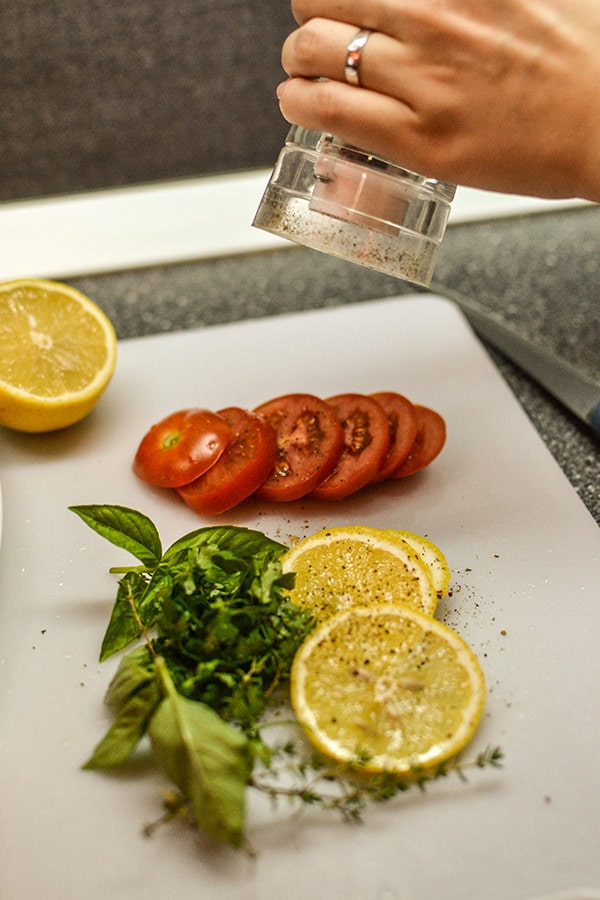 Seasoning with pepper slices of lemons and tomatoes