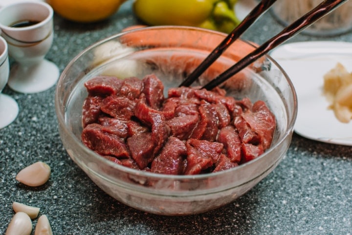 Marinated meat into a plate with garlic and ginger.