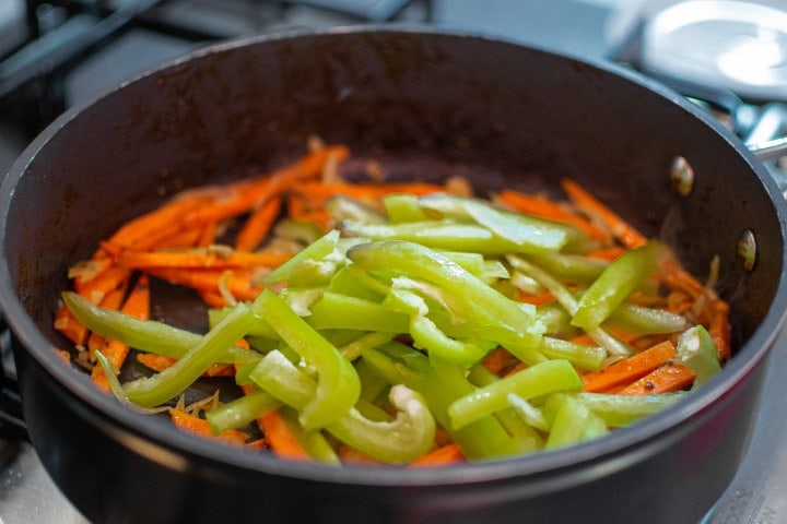 Onions, carrots and bell pepper frying in a pan