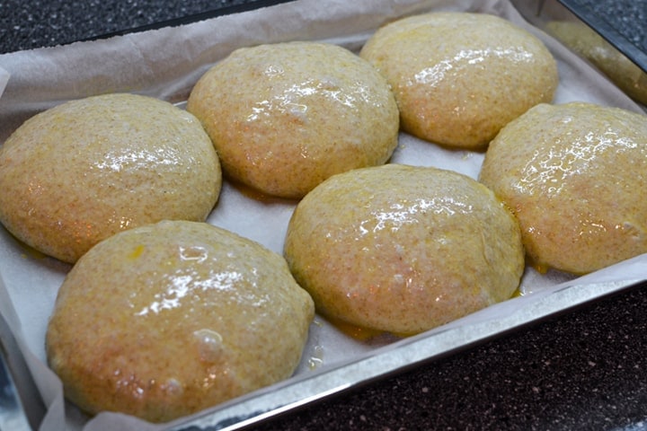 Six unbaked hamburger buns greased with a beaten egg.
