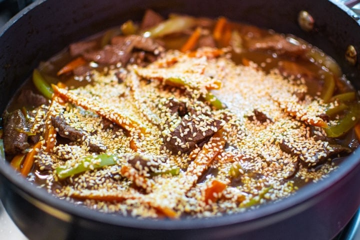 Meat with vegetables and seasame seeds in a pan