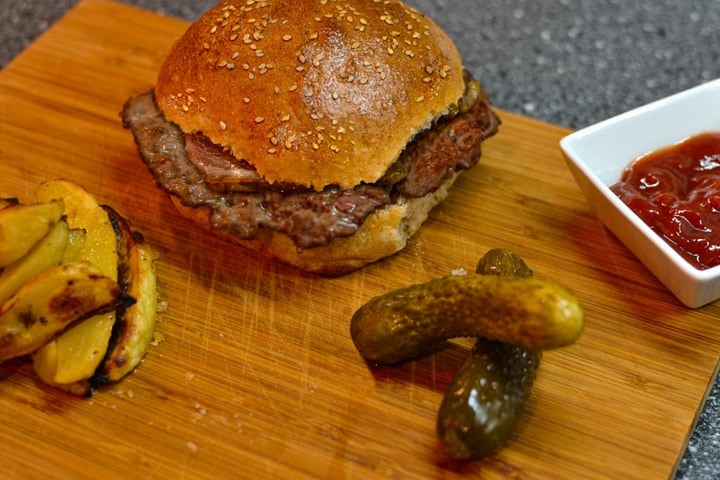 Homemade burger with homemade burger buns with fried potatoes and cucumbers.