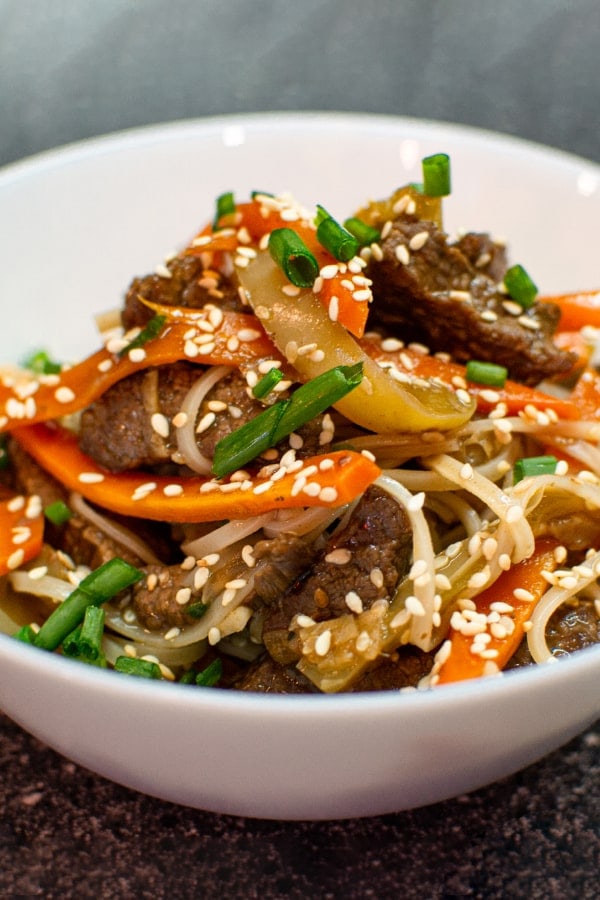 Plate with noodles, vegetables, meat and sesame seeds