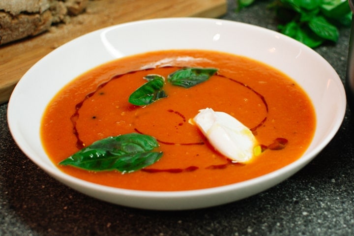 homemade creamy tomato soup with ricotta and basil leaves