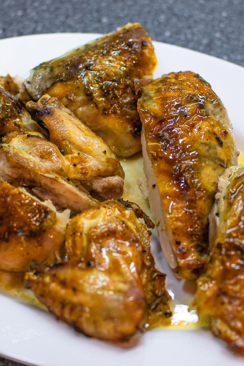 Roasted Chicken with Garlic and Herbs on white table.