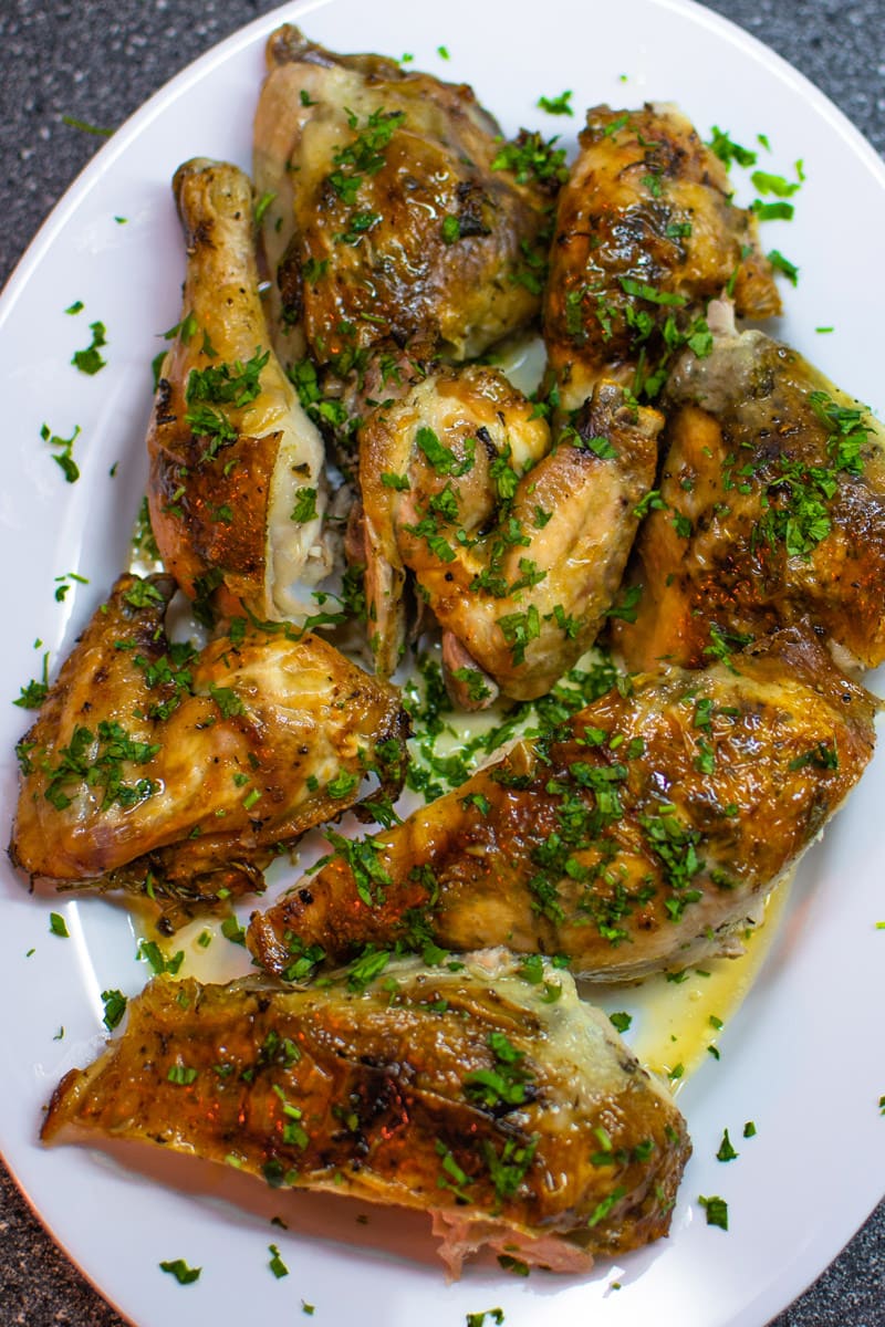 Roasted chicken on plate with herbs.