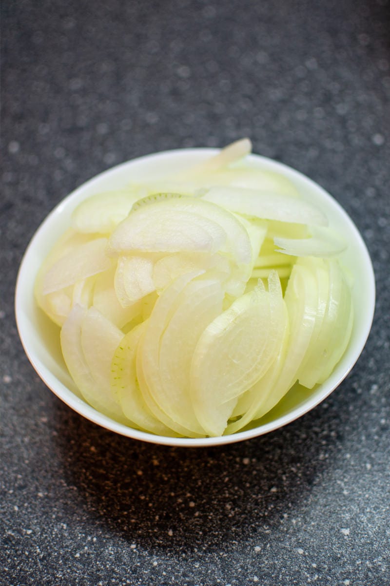 Sliced onions in a bowl on table.
