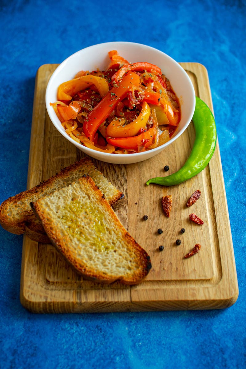 Delicious Peperonata on wood table with roasted bread