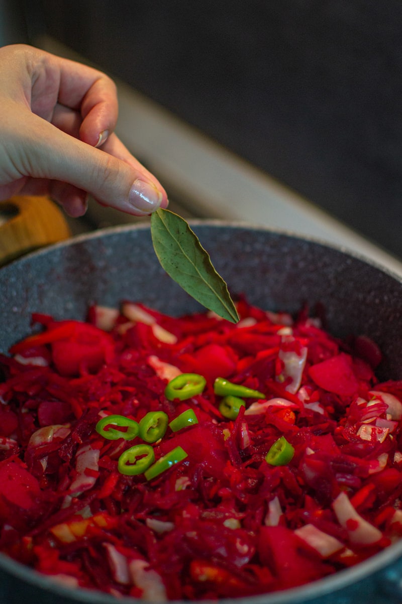Adding aromatic herbs into red borscht soup