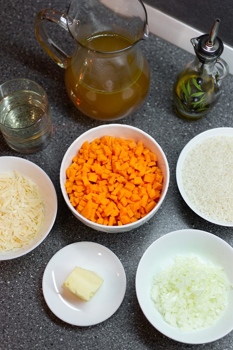 Chopped carrots, onions, cheese and rice on white plates on table