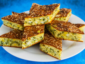 Spring Onion Tart slices on a white plate on a rich blue background.