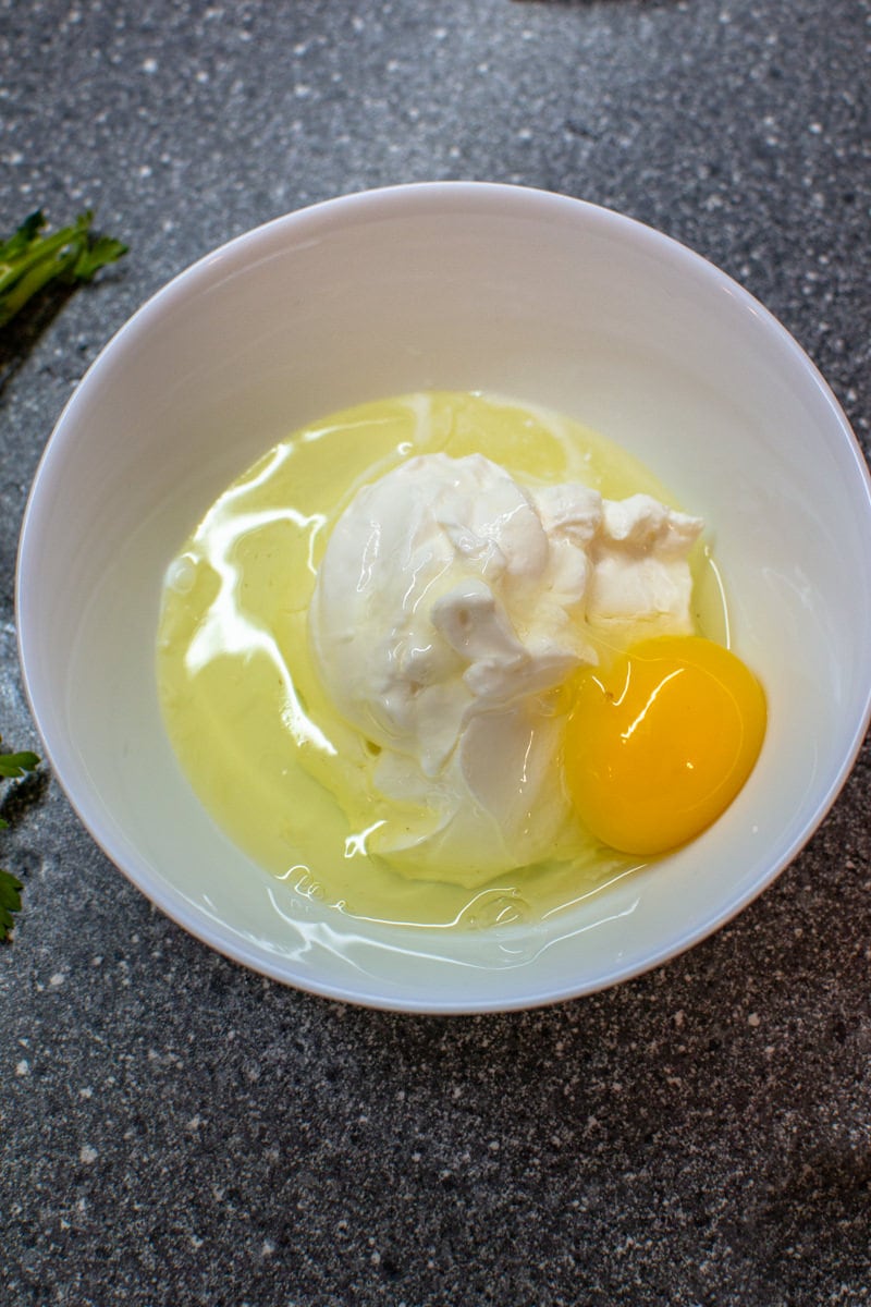 Sour cream with a raw egg in a white plate.