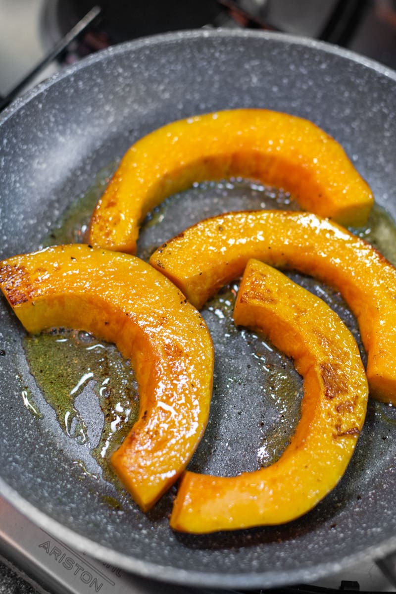 4 Fried Slices of pumpkin on a gray pan.
