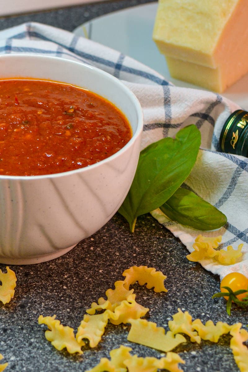 Basic tomato sauce in a big white bowl with pasta on the table.