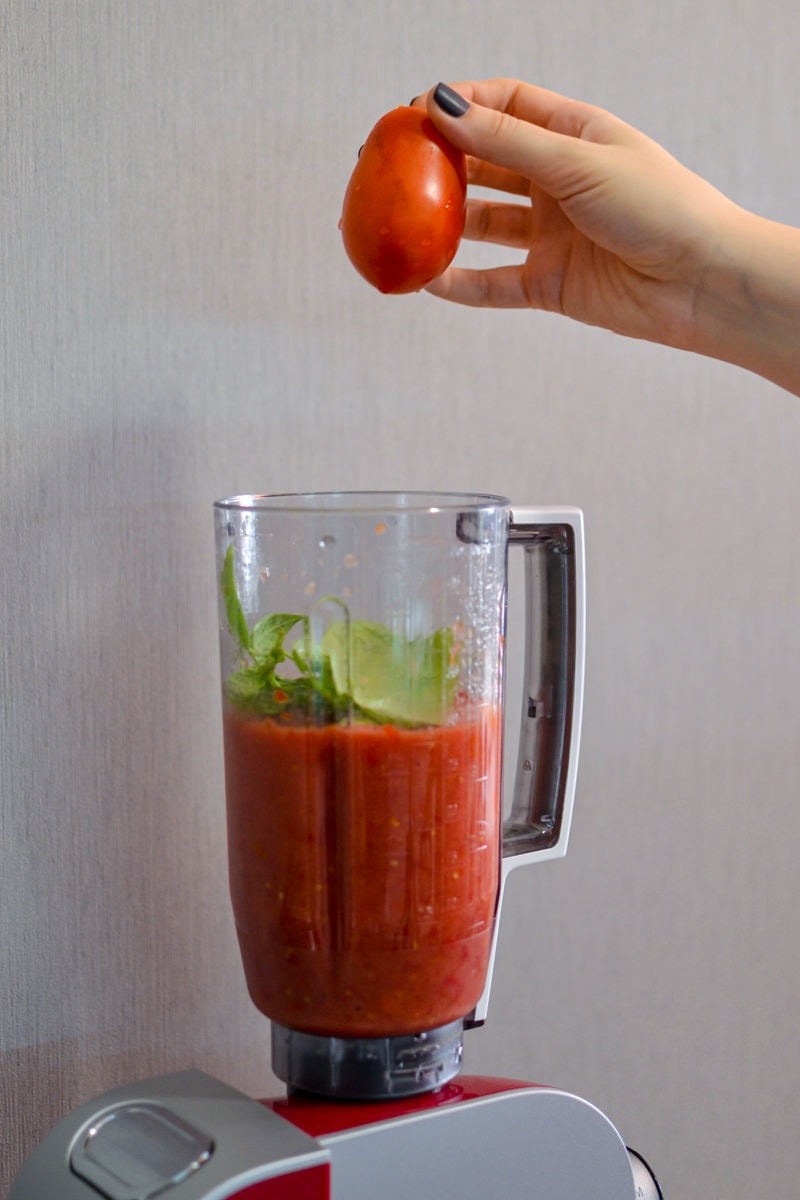 Adding a red tomato over the tomato sauce