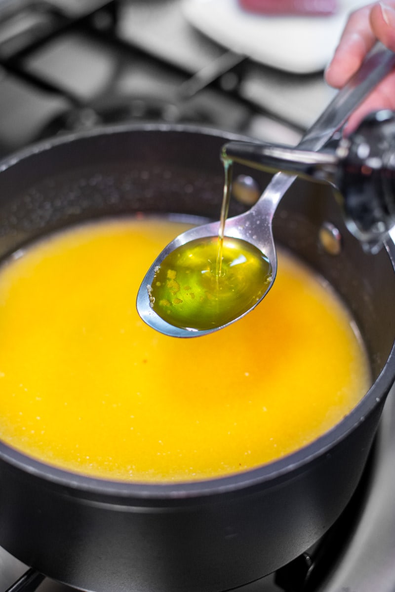 Pouring olive oil in a table spoon over the creamy polenta.