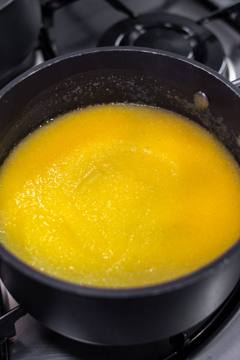 Creamy Polenta on the stove in a dark pan