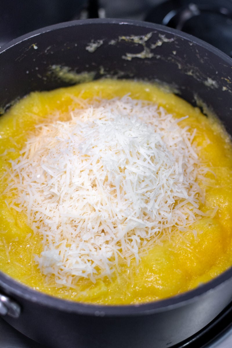 Creamy Polenta with Parmesan on the stove in a dark pan
