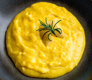 Creamy Polenta with Parmesan in a dark plate on a marble table.