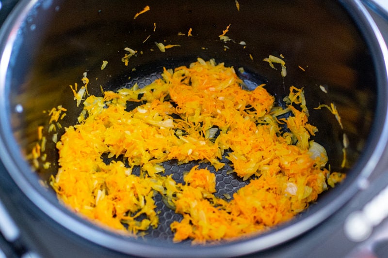 Frying chopped carrots in a dark pan.