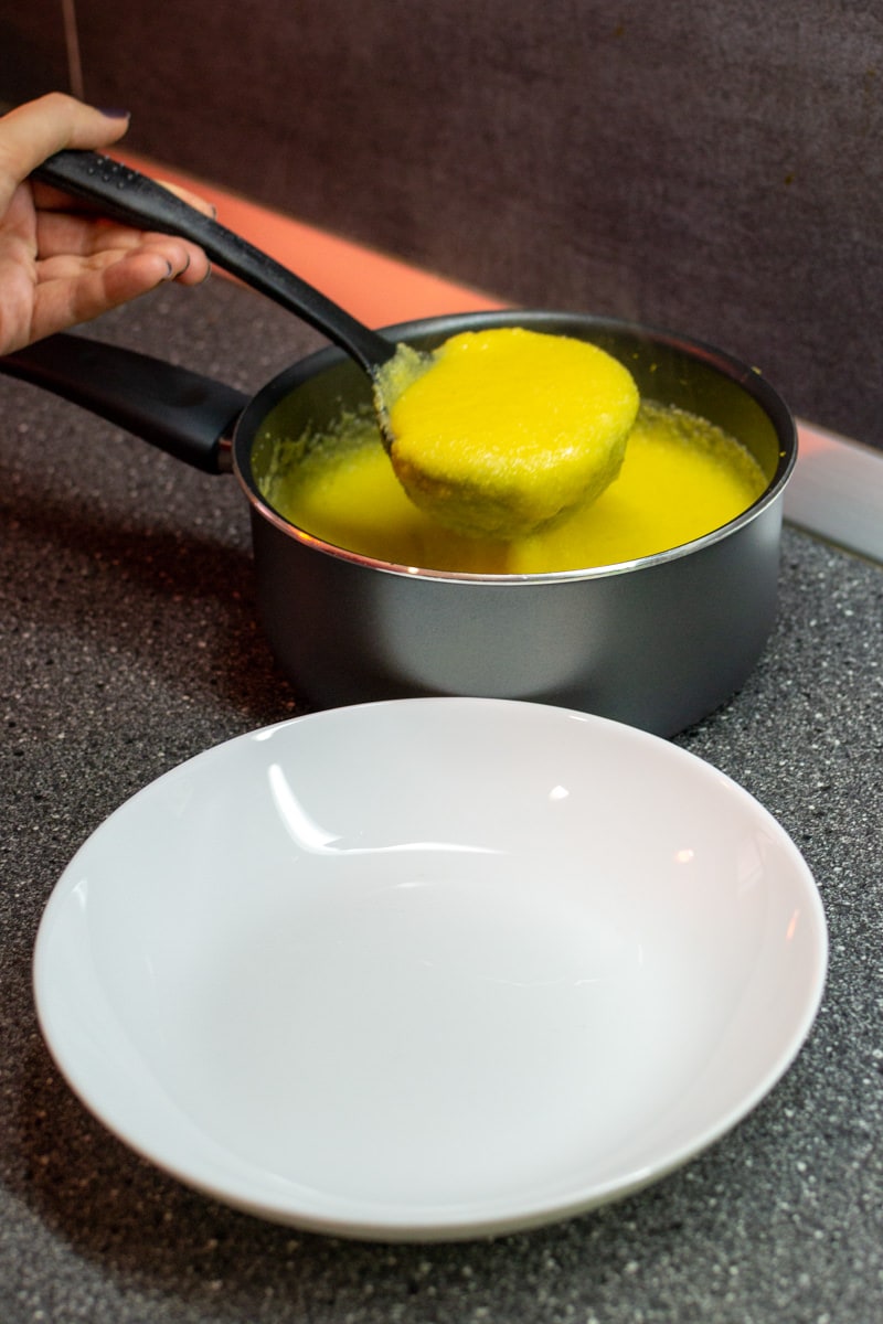 Pouring polenta on a white plate.