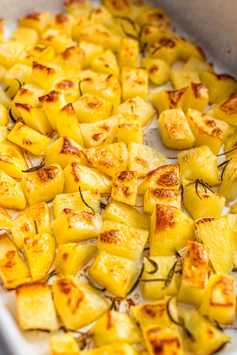 Roasted parmentier potatoes on a white oven tray.