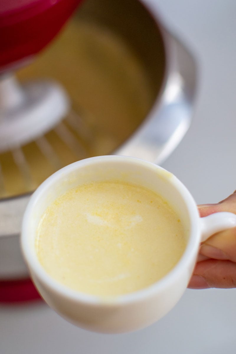 Woman hand holding Melted butter in a small white cup.