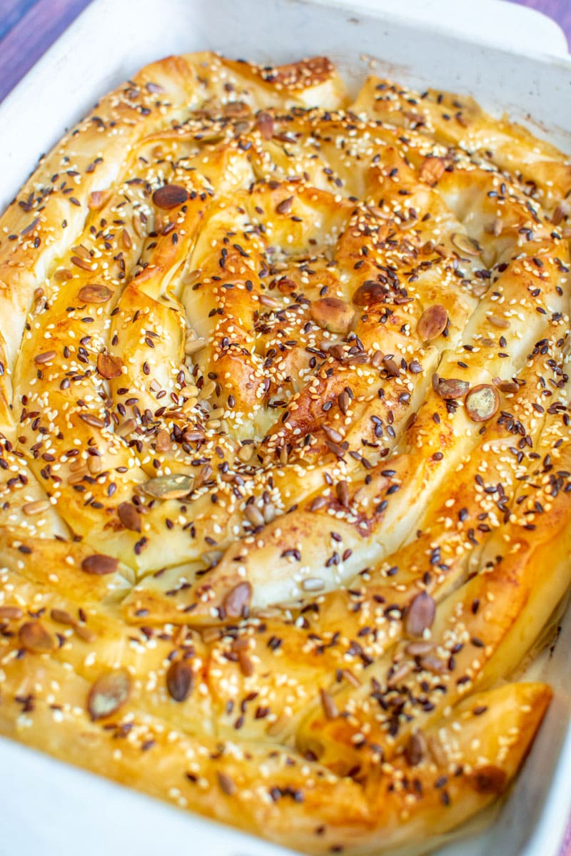 Bosnian Cheese Pita with seeds in a white oven tray.