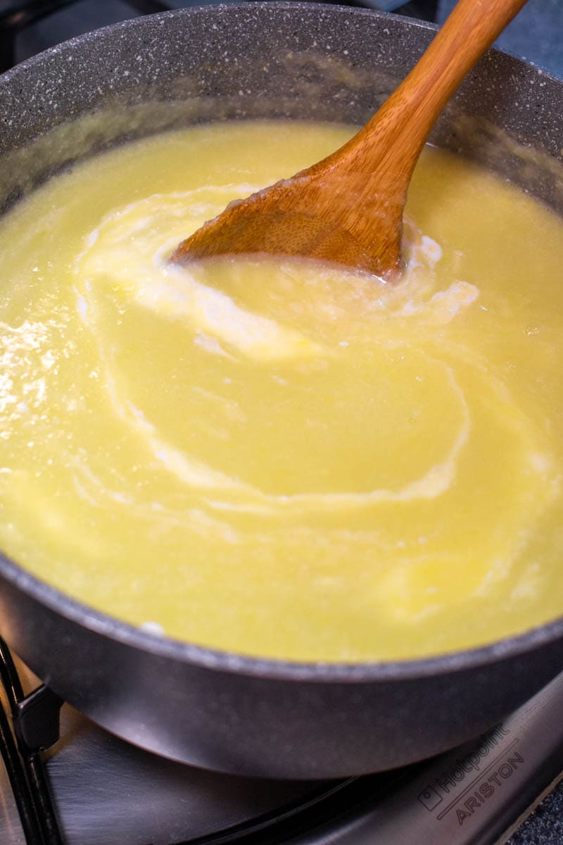 Mixing cauliflower soup with a wooden spoon.