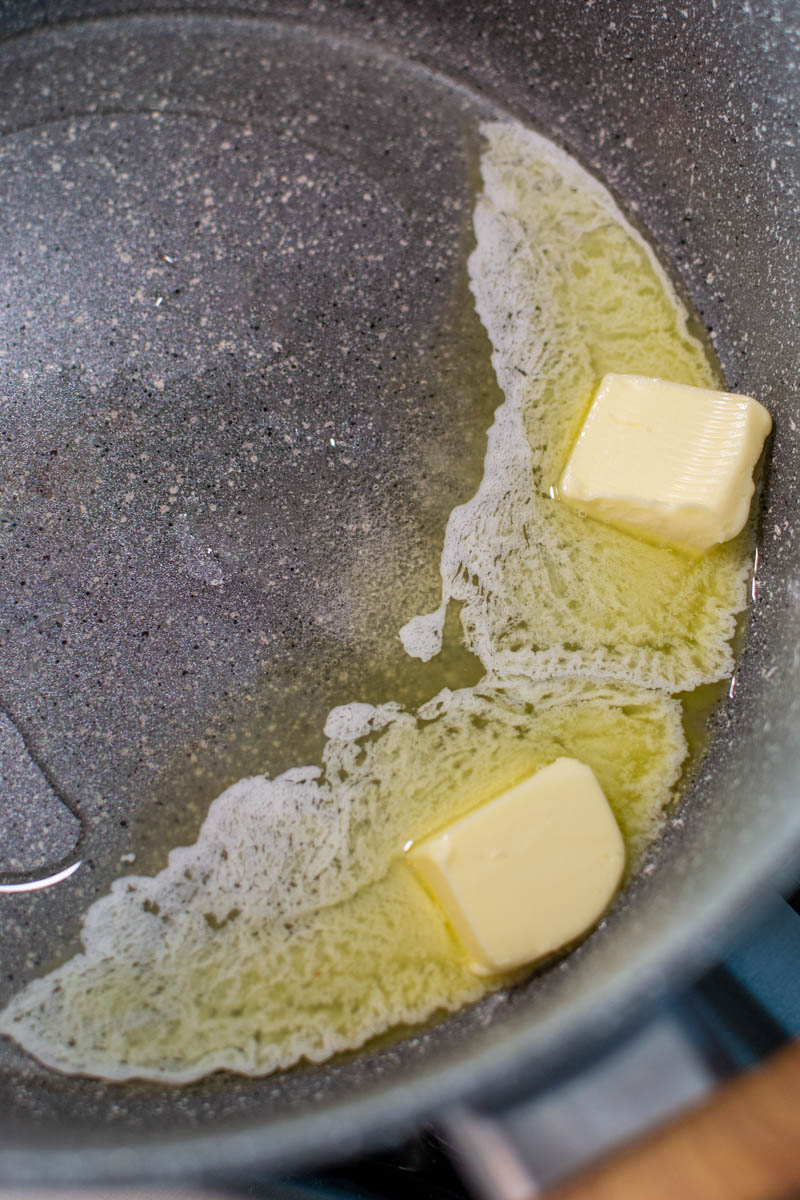 Melted butter with olive oil in a gray pan.