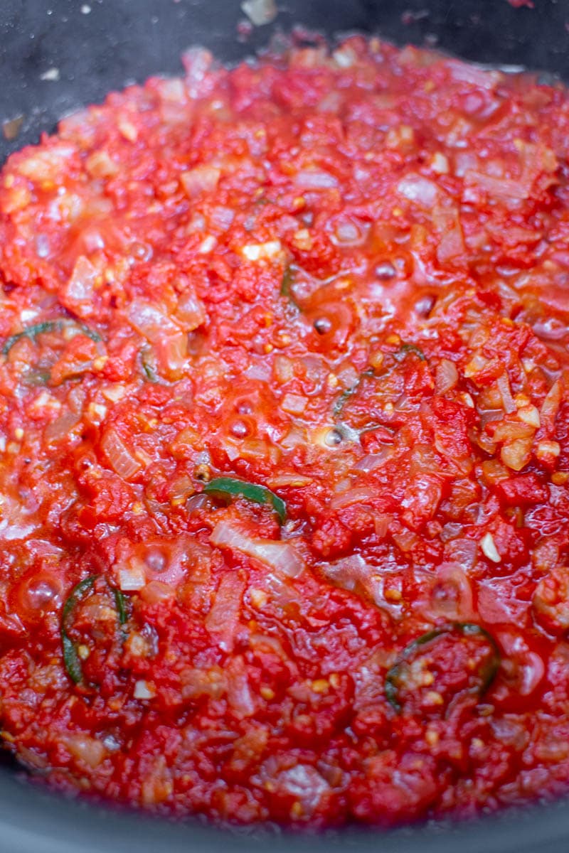 Frying tomato sauce with onions and hot peppers.