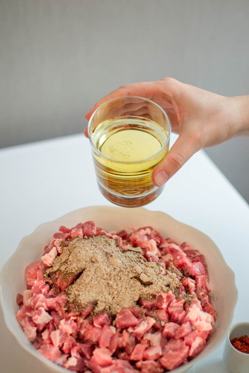 Pouring white wine over ground meat for Sicilian sausages.