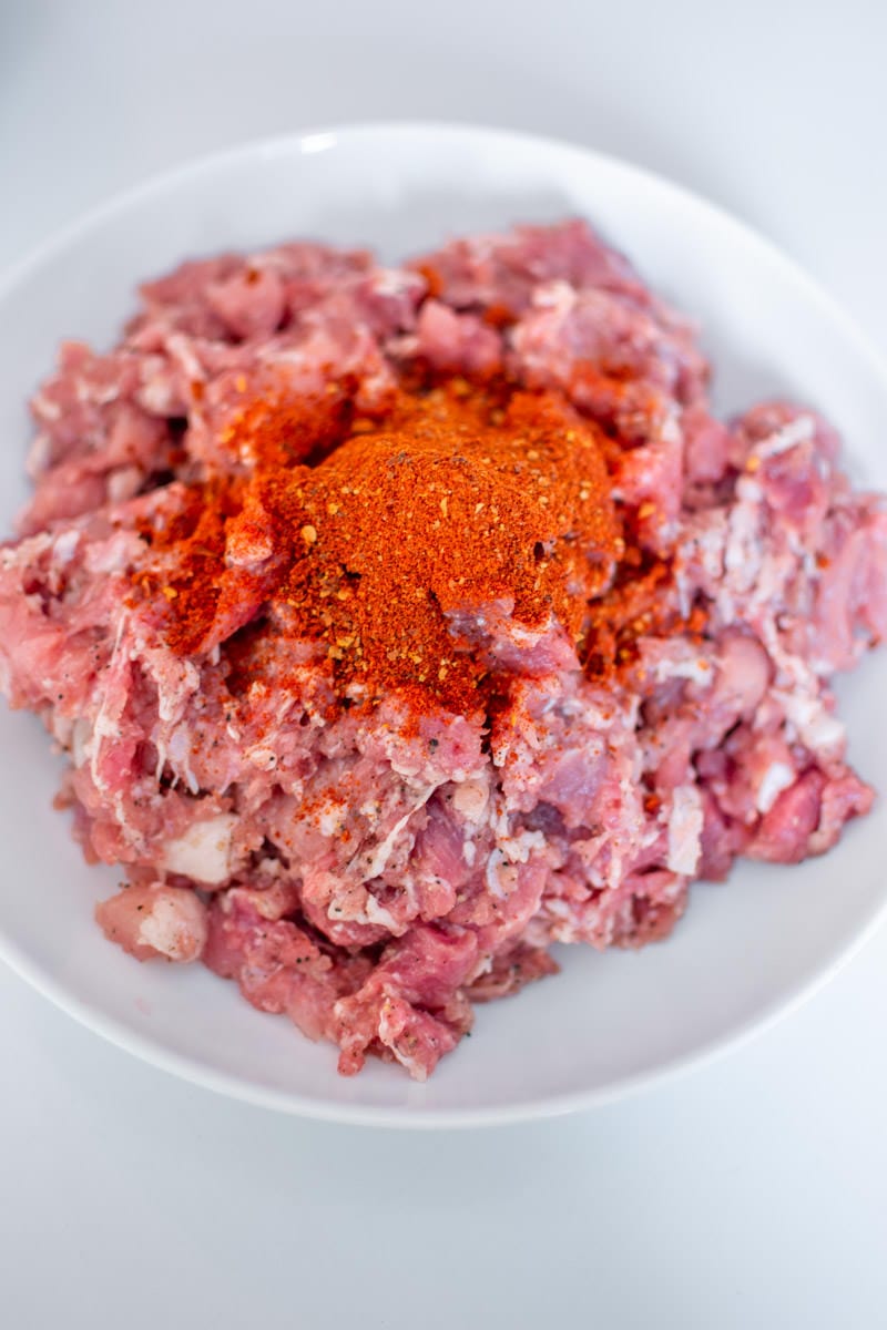 Ground meat with smoked paprika on top for making Sicilian homemade sausages.