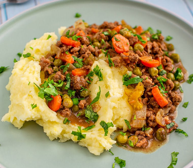 Smashed potatoes with grounded meat on a plate.