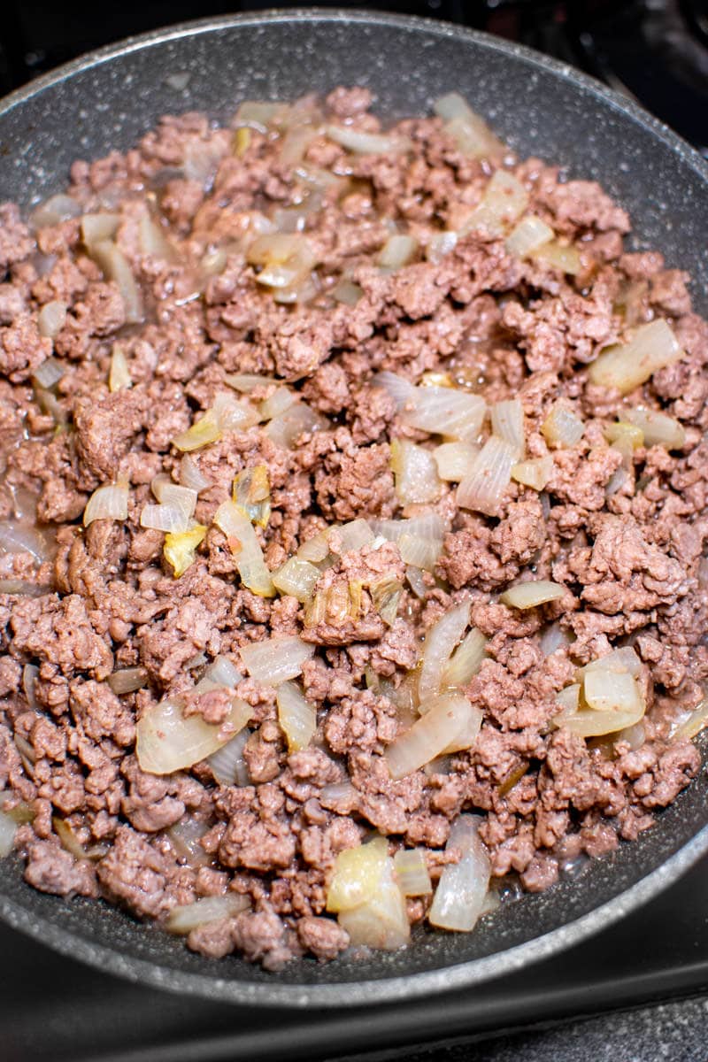 Ground meat with chopped onions in a sauce pan.