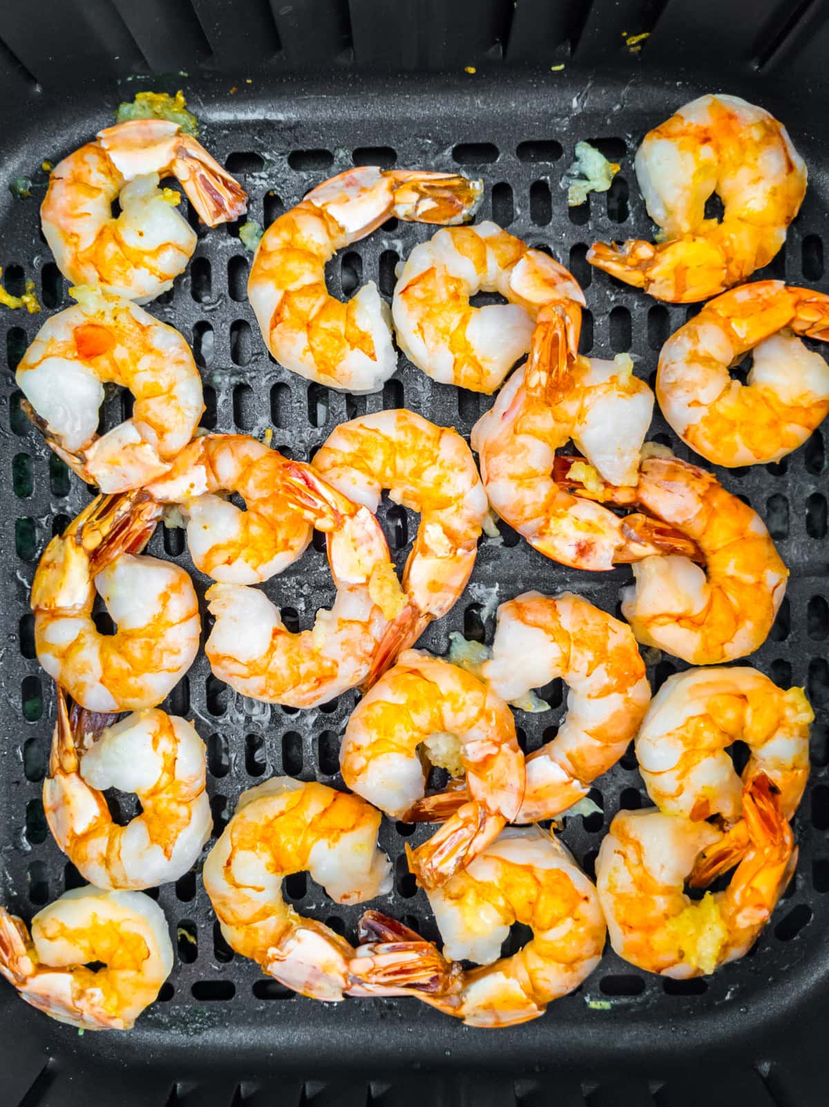 Cooked shrimps with butter and garlic in the air fryer basket.