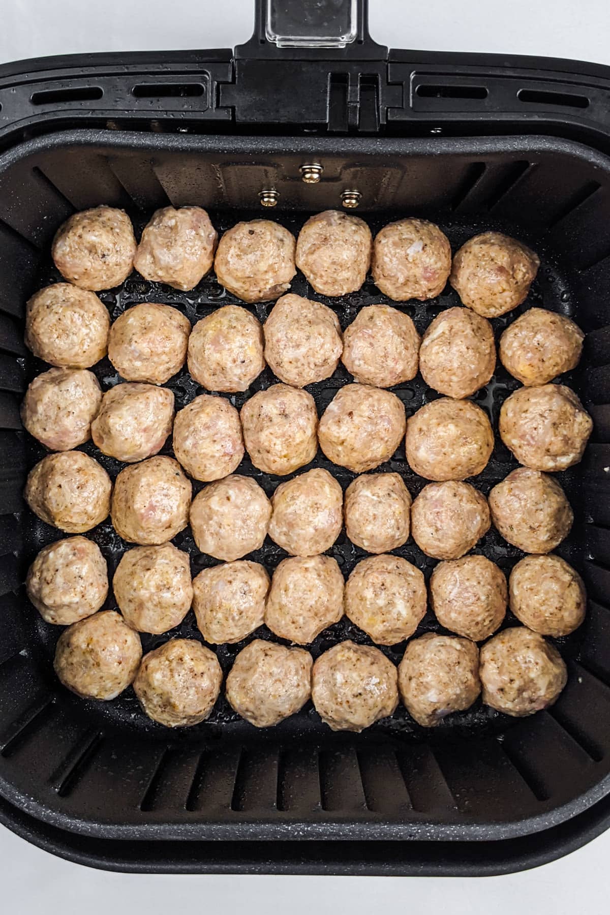 Top view of an air fryer basket with homemade chicken meatballs.