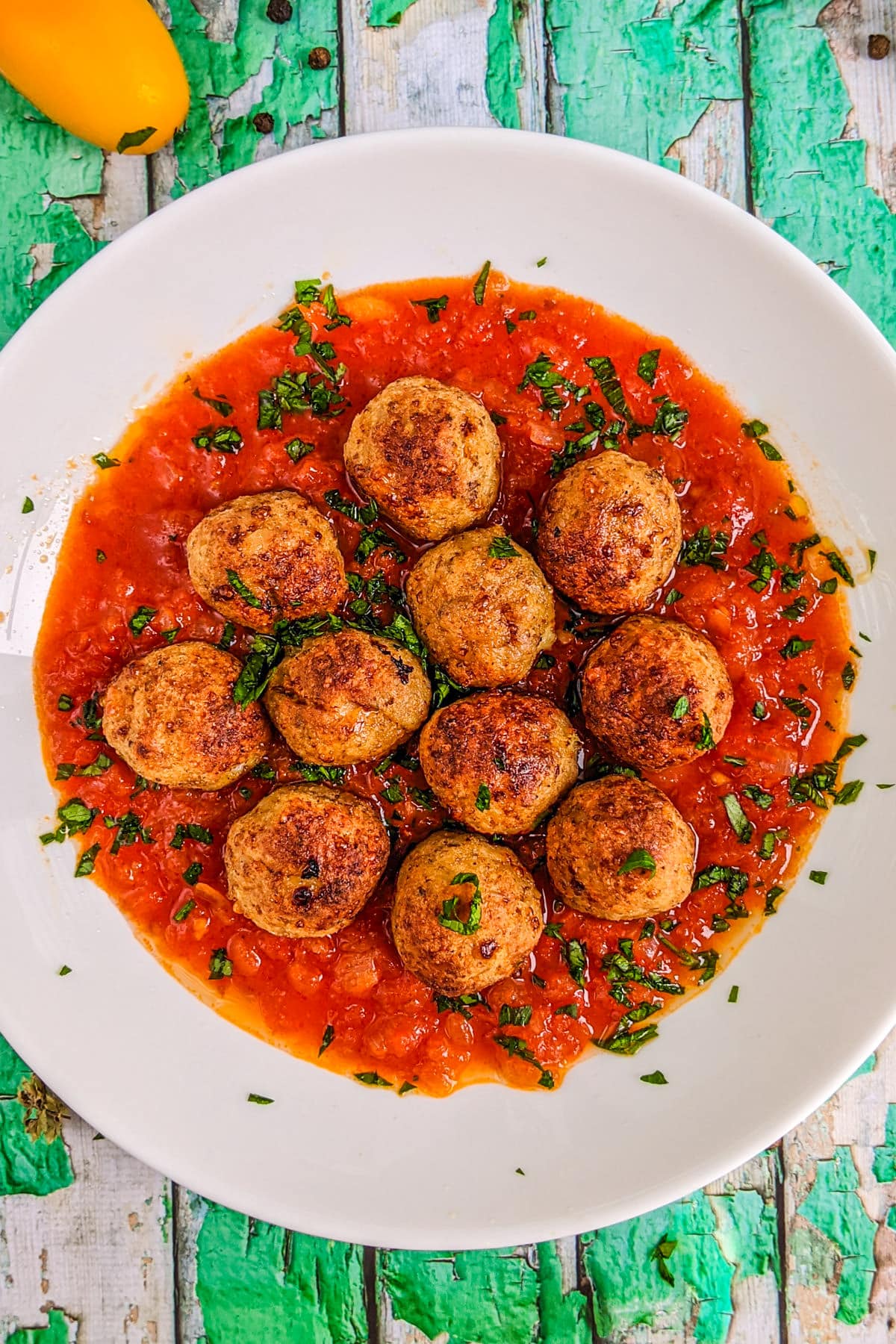 Top view of a plate with chicken meatballs with tomato sauce.
