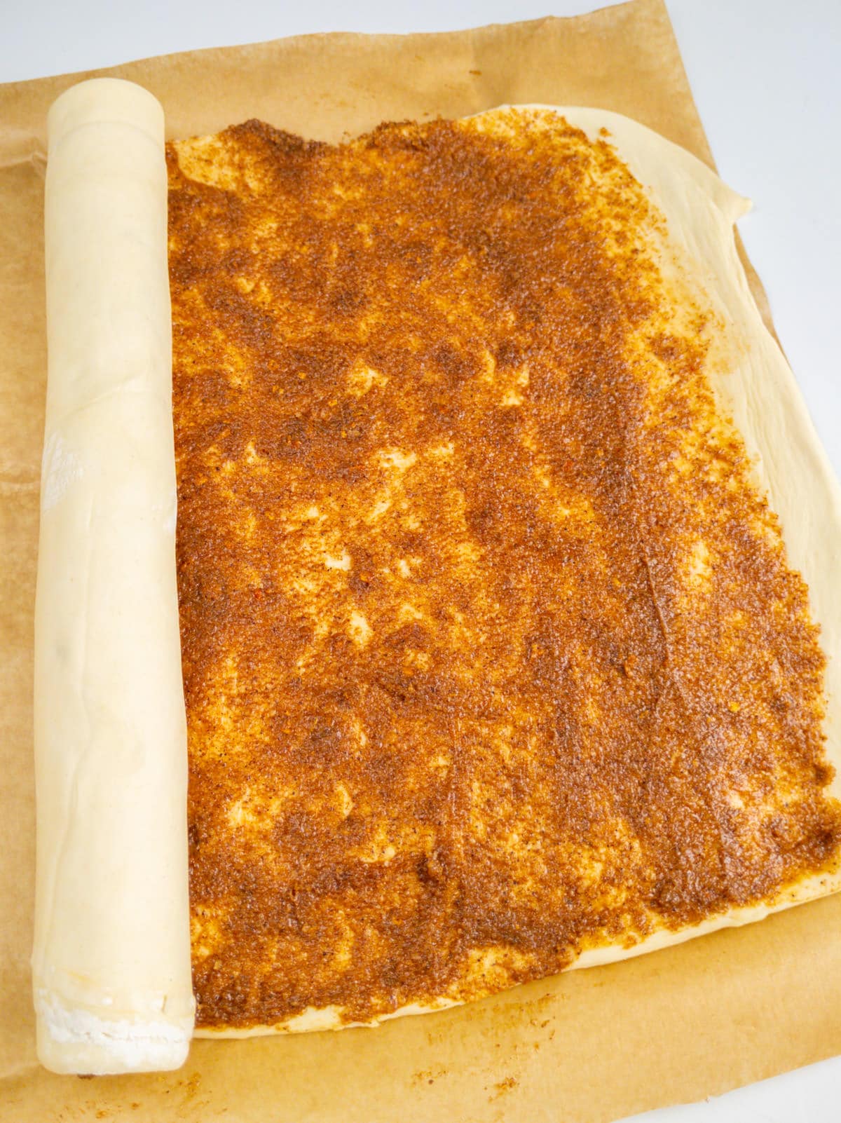 Pastry dough on a baking paper covered with cinnamon pasta.