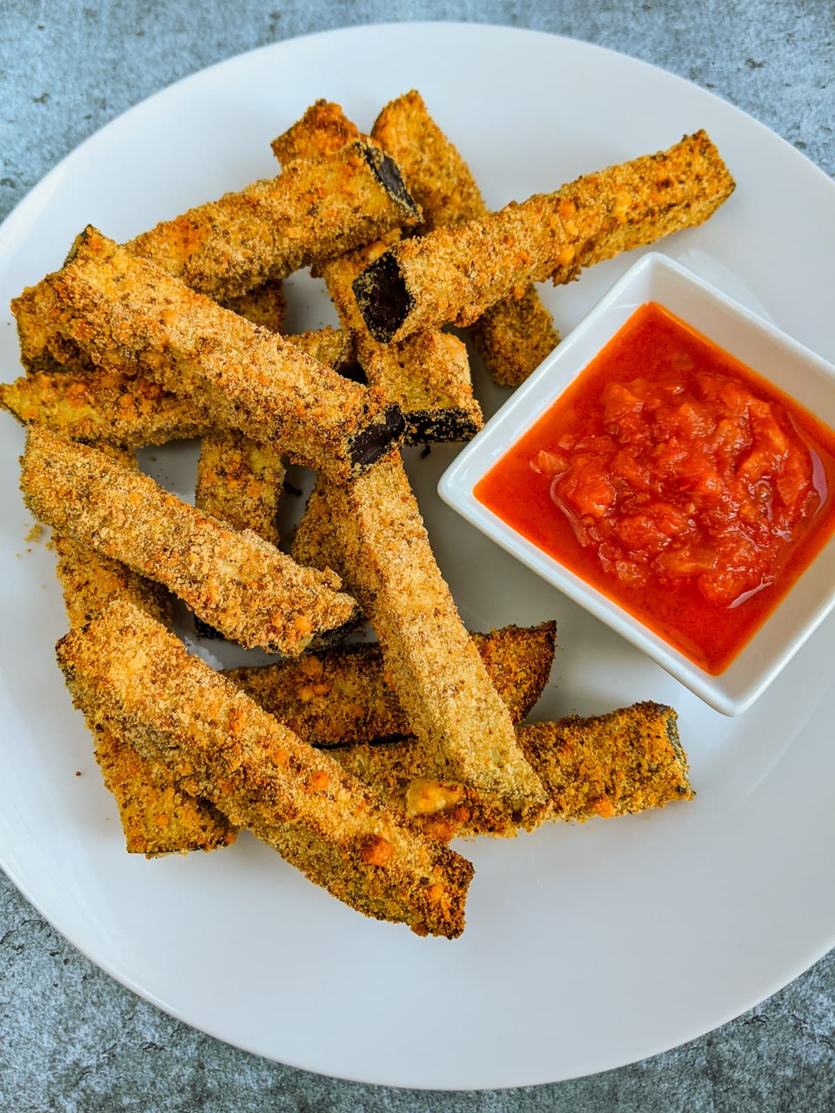 Tomato sauce with eggplant fries on a concrete table.