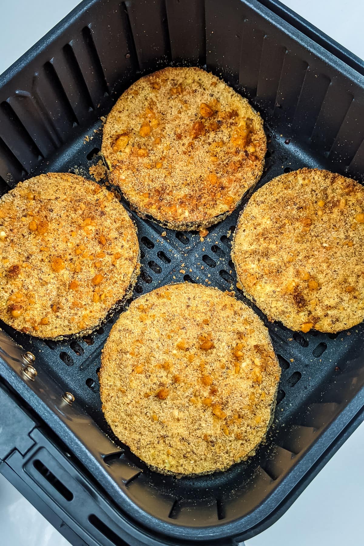 Close look of panko-crusted slices in an air fryer basket.