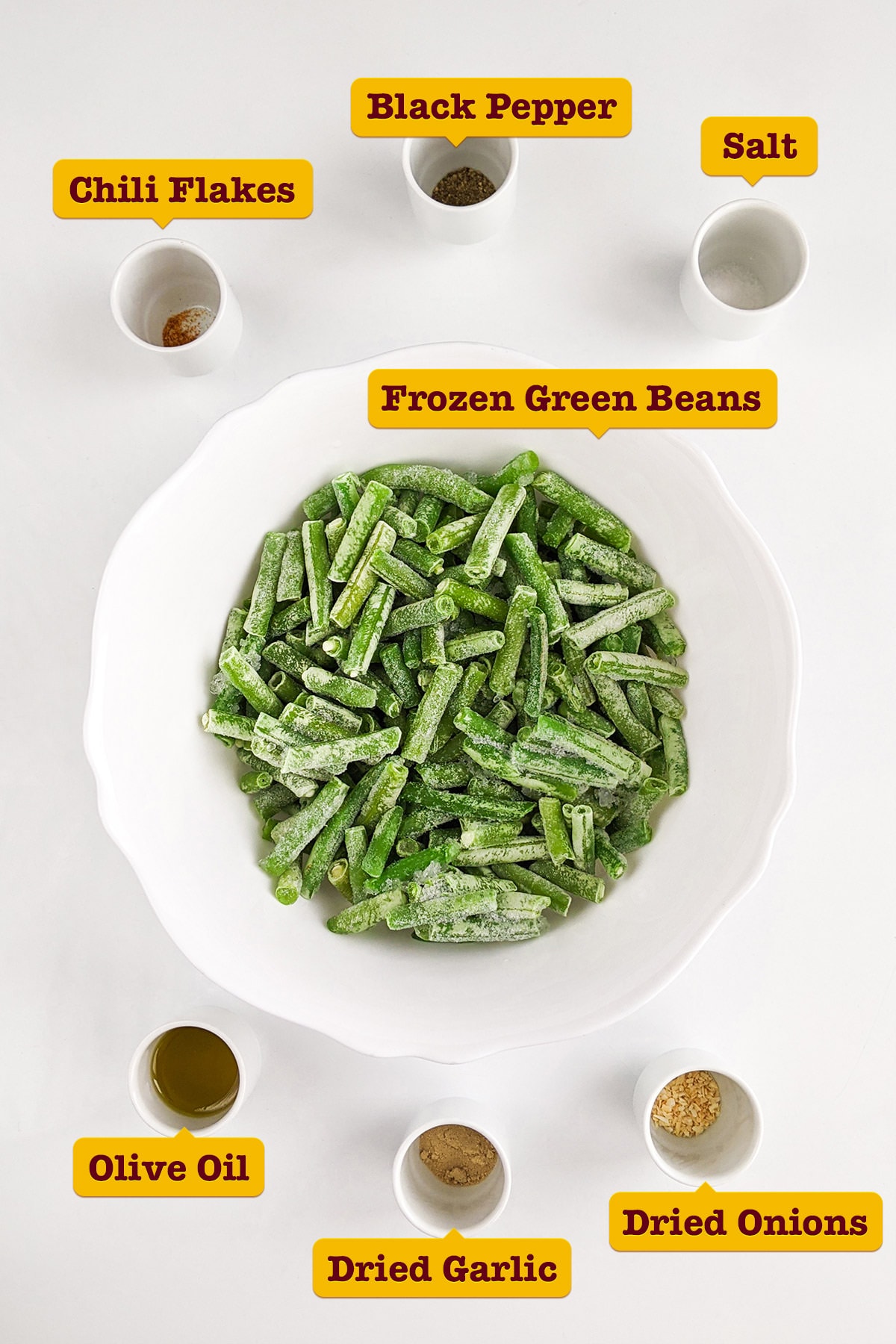 Top view of frozen green beans with spices on a white table.