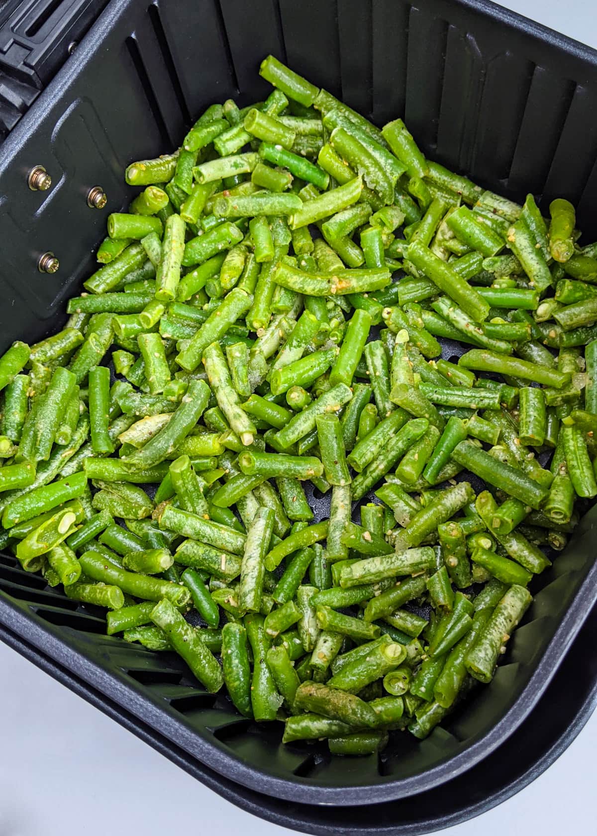 Top view of frozen green beans in the air fryer basket.