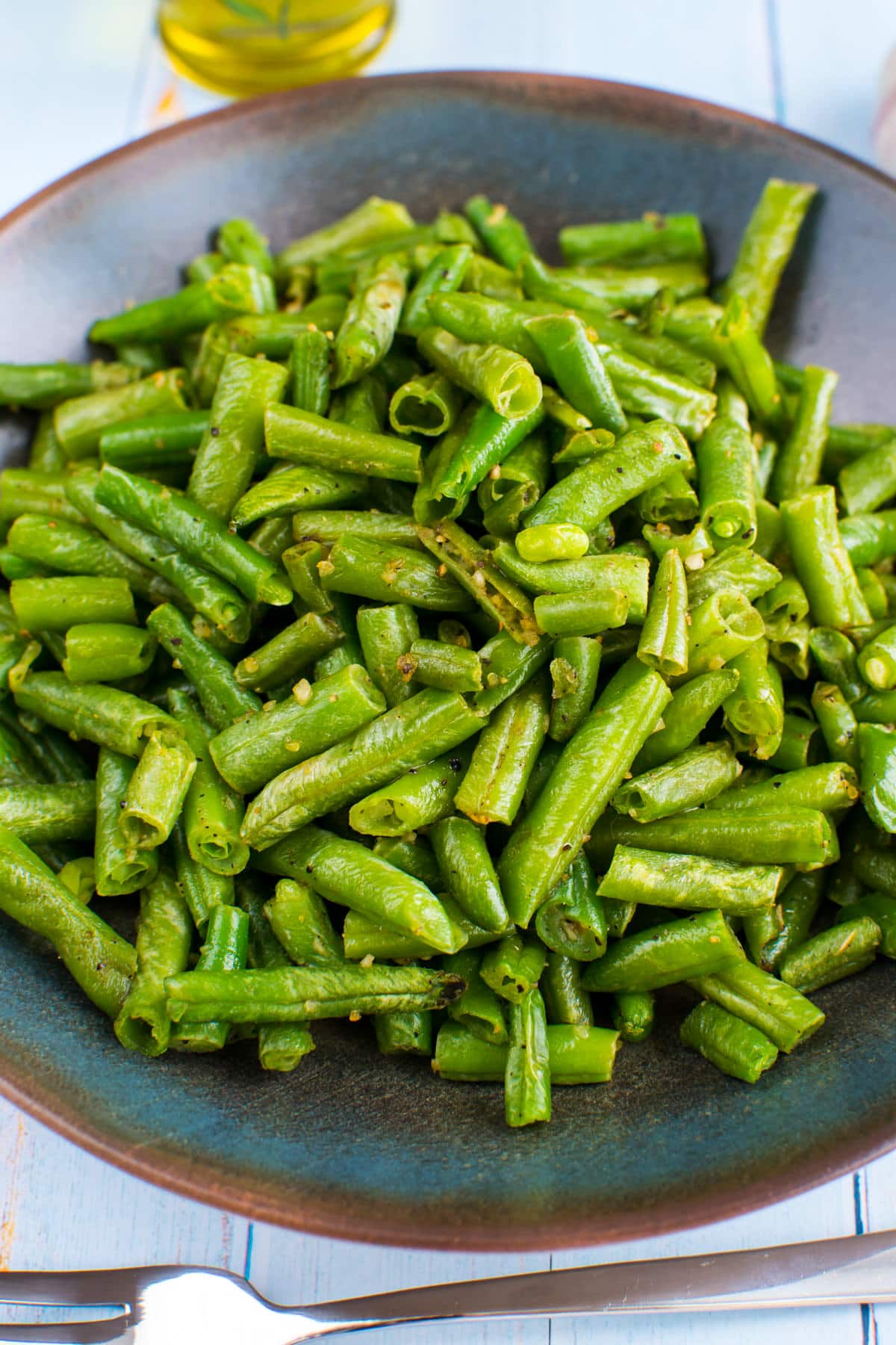 Plate with green beans cooked in the air fryer on a wooden table.