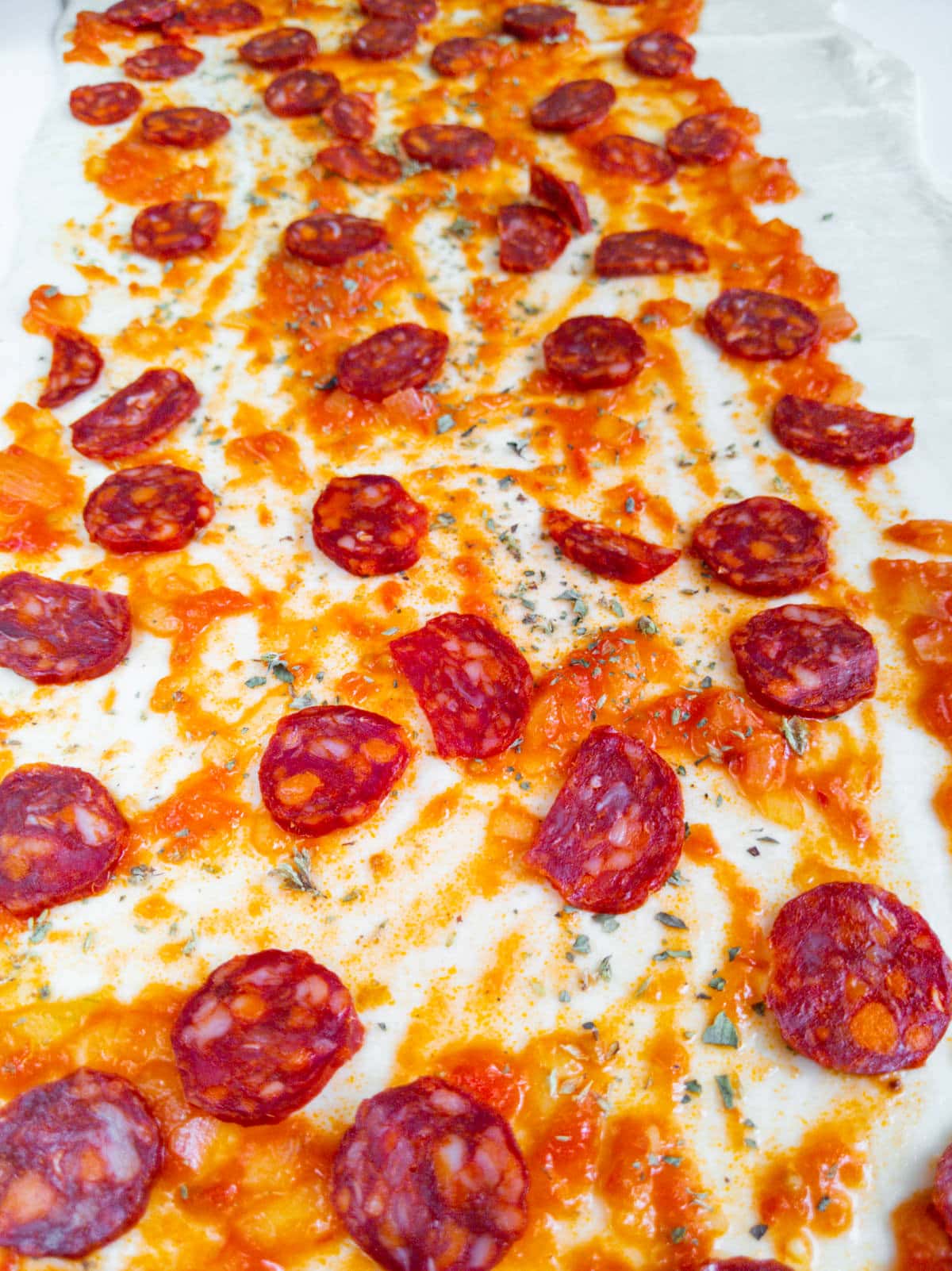 Close up look with tomato pizza sauce and chorizo slices.