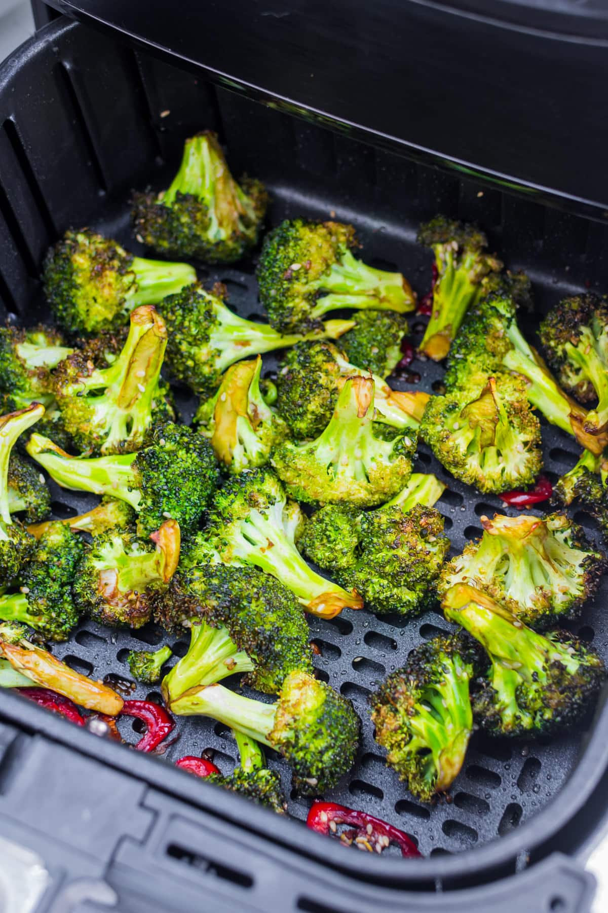 Air fried broccoli with red hot pepper on an air fryer pan.
