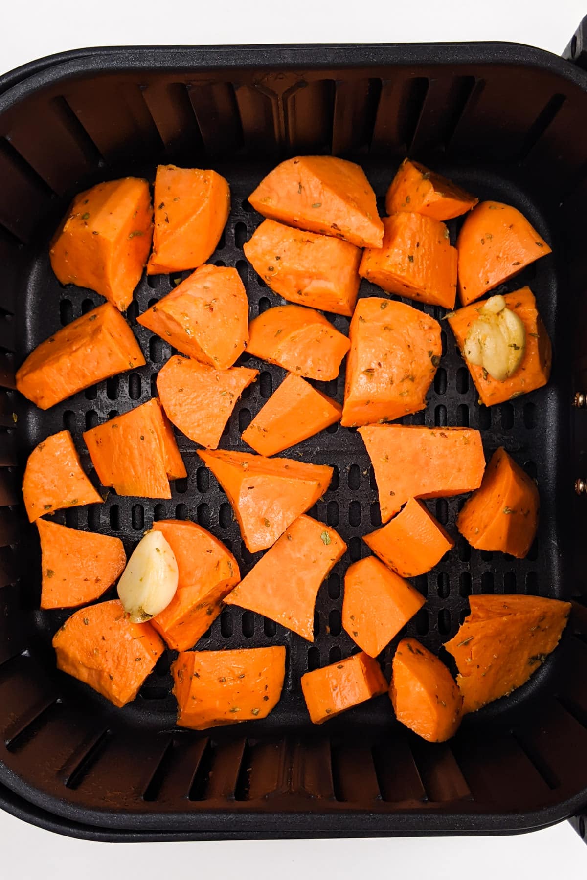 Top view of sweet potato chunks in the air fryer basket.
