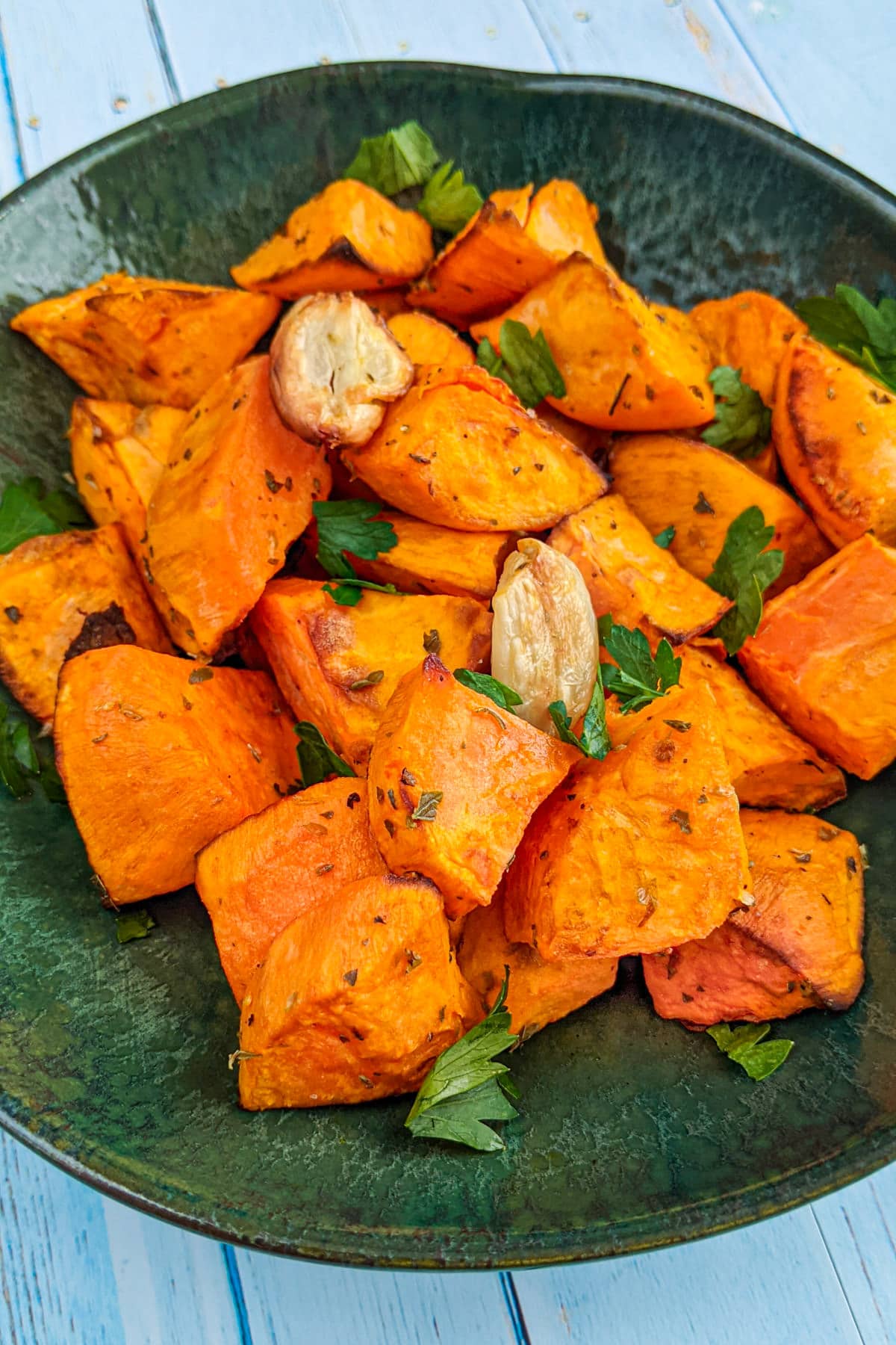 A plate with sweet potato bites with garlic and parsley.