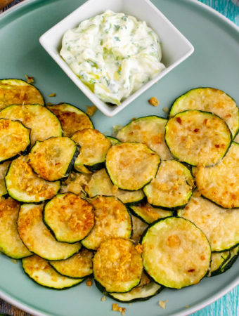 Close top look of air fryer zucchini chips with white sauce.