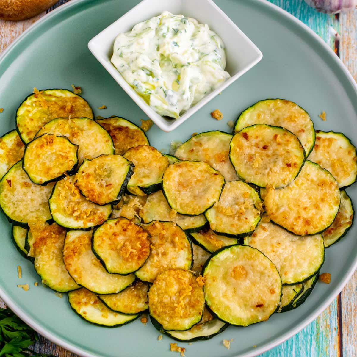 Close top look of air fryer zucchini chips with white sauce.